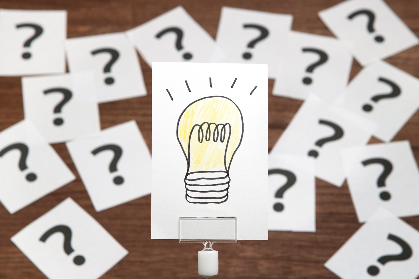 note card with a lightbulb, surrounded by note cards with question marks