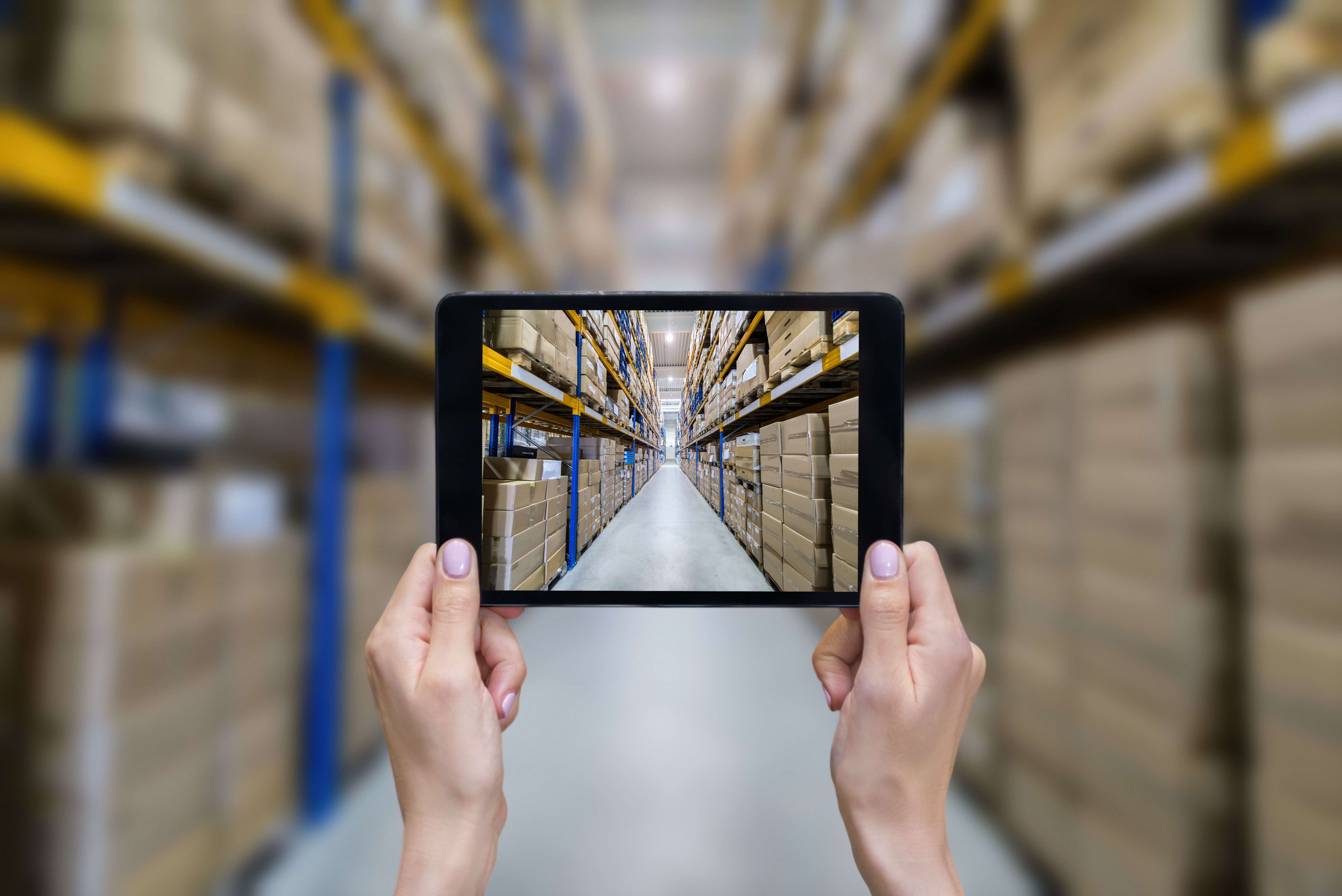 tablet taking photo of warehouse aisle with everything blurred except for the tablet screen