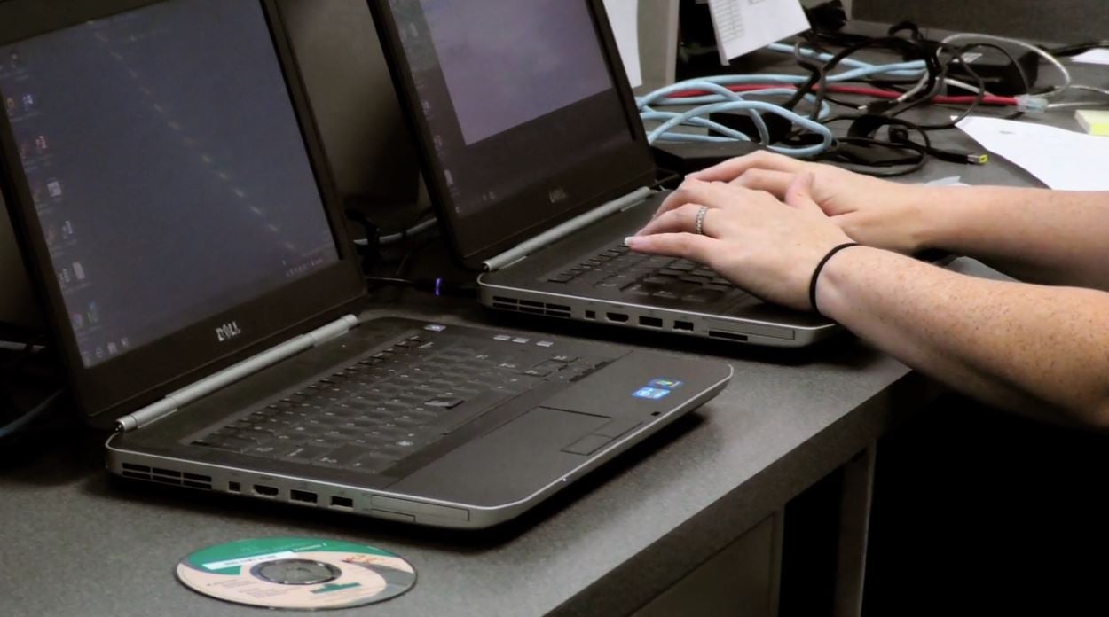 woman's hands typing on laptop next to another laptop