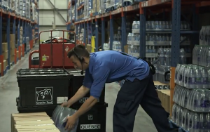 man in warehouse stacking cases of water png