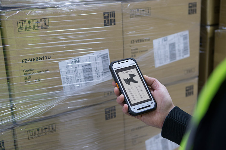 warehouse employee looking at boxes and mobile device