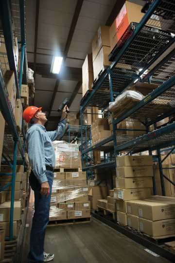 warehouse worker with hard hat doing long-range scanning of boxes on the racks with device