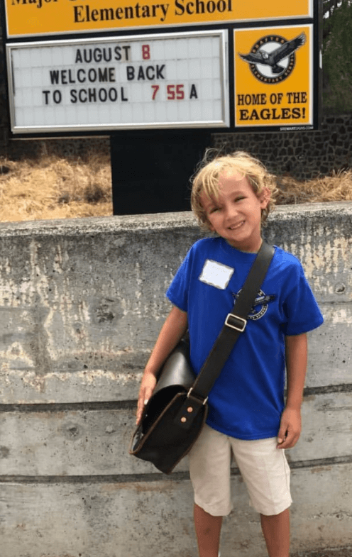 kid taking photo outside of elementary school on first day