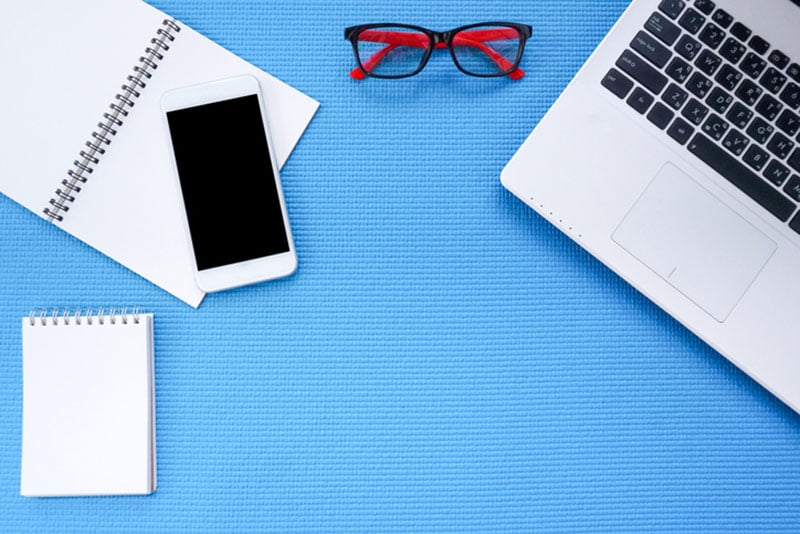 laptop, phone, notebooks, glasses w blue background