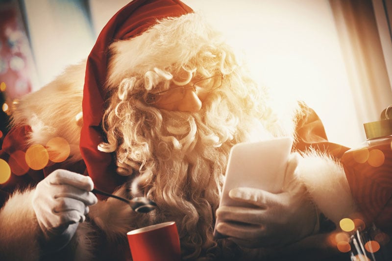 santa sipping cocoa while looking at tablet