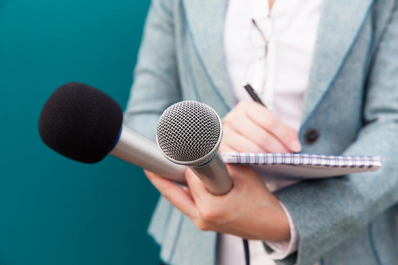 woman holding notepad and two mics