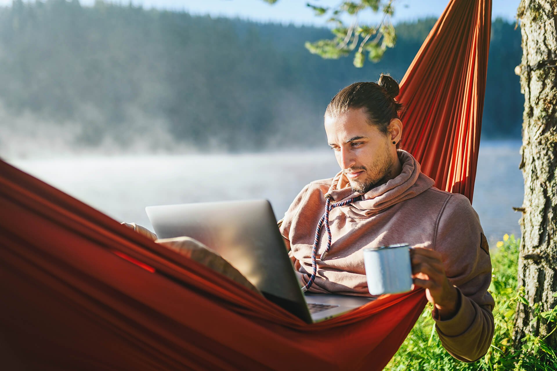 Person viewing a laptop while laying in a hammock.