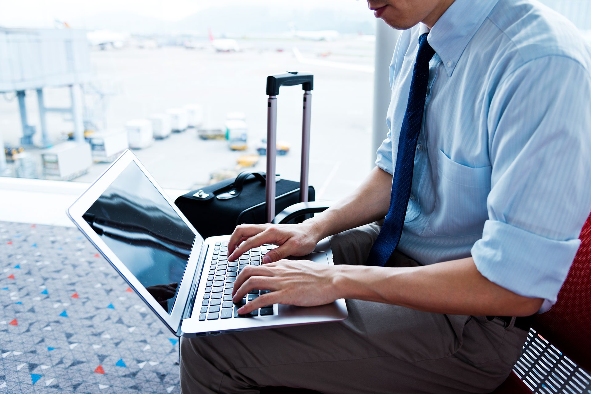 Man in business attire works on laptop at airport