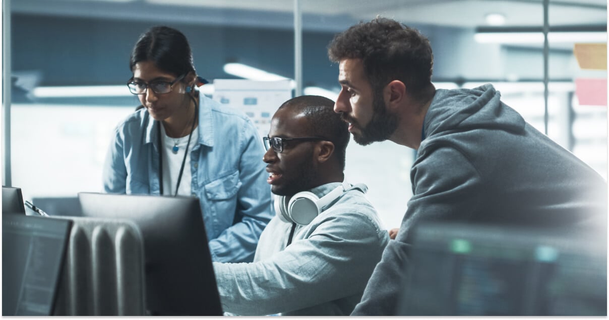 Three people interacting with a desktop computer.