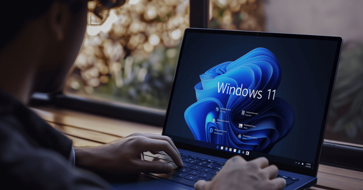 Laptop screen with Windows 11 graphic.