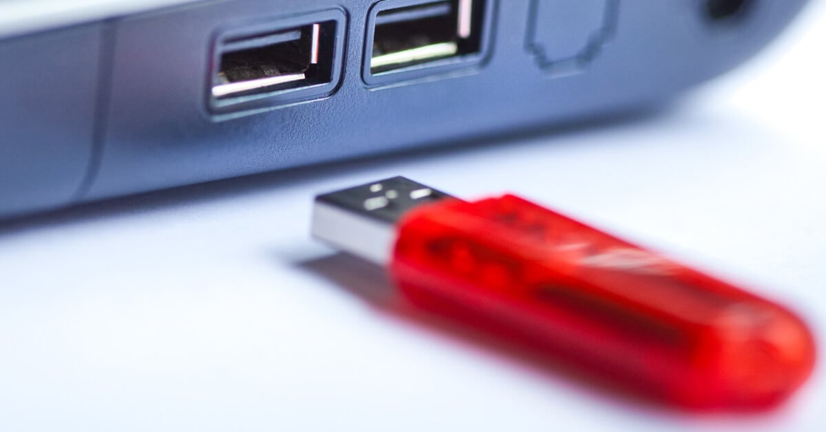USB stick next to a USB port on a computer.