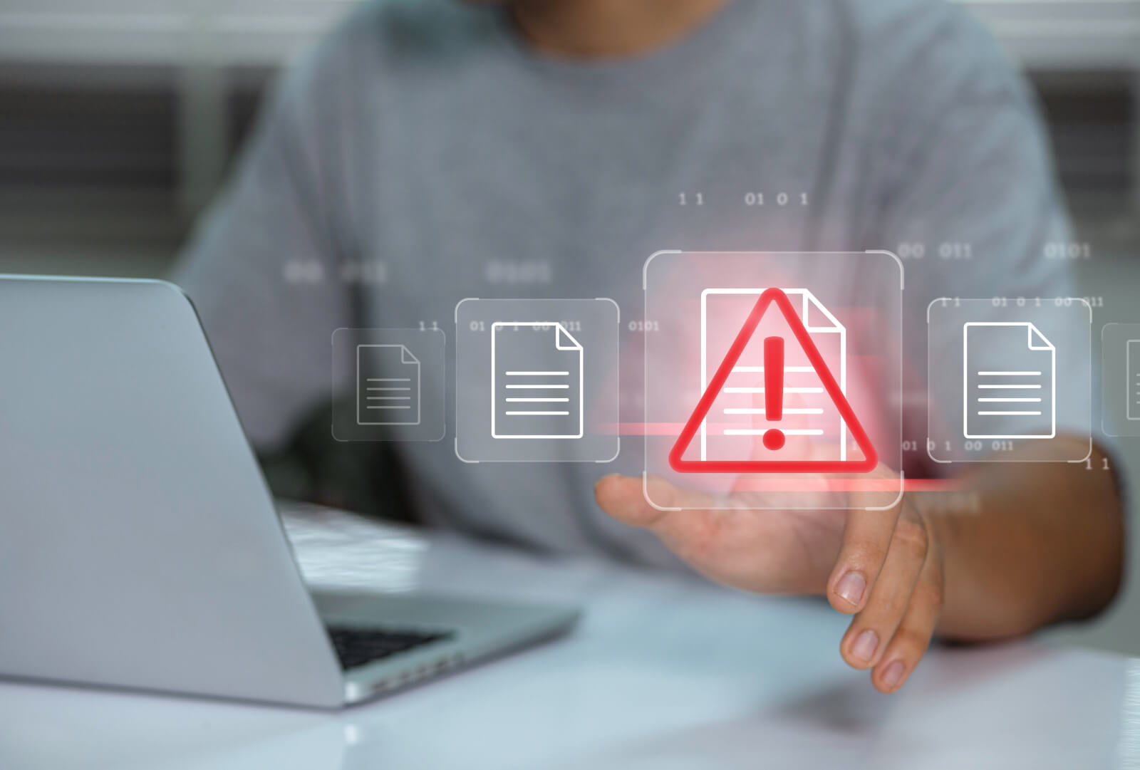Holographic desktop app icons floating in front of a person sitting and working on a laptop.