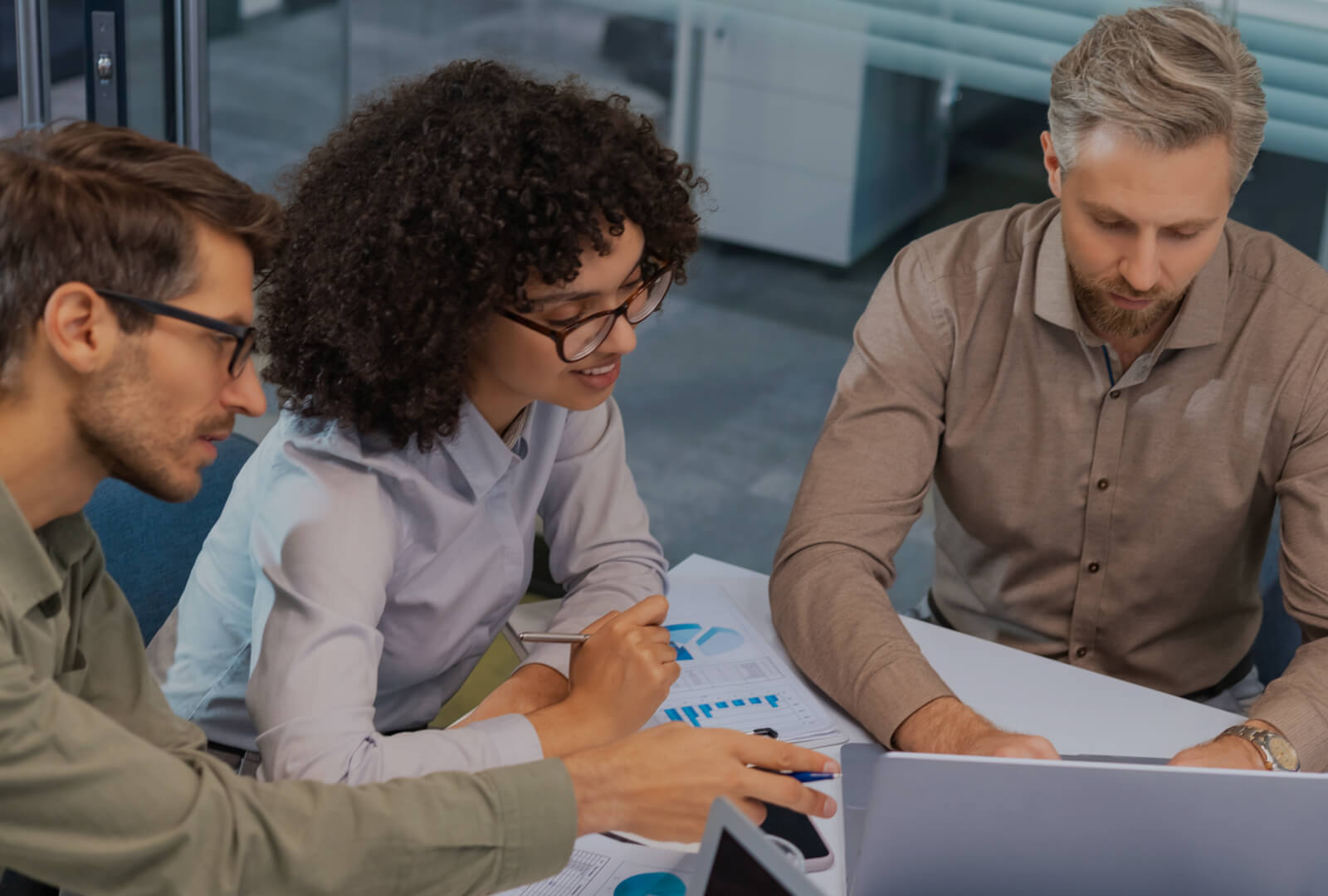 A group of three people interacting with a laptop.