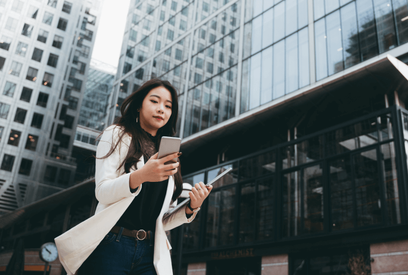 Woman interacting with a smartphone outside of an office building.