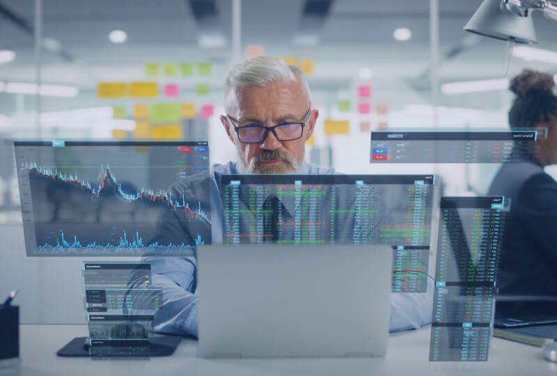 A man in an office interacting with a laptop while holographic images of the contents of the laptop's screen float around him.