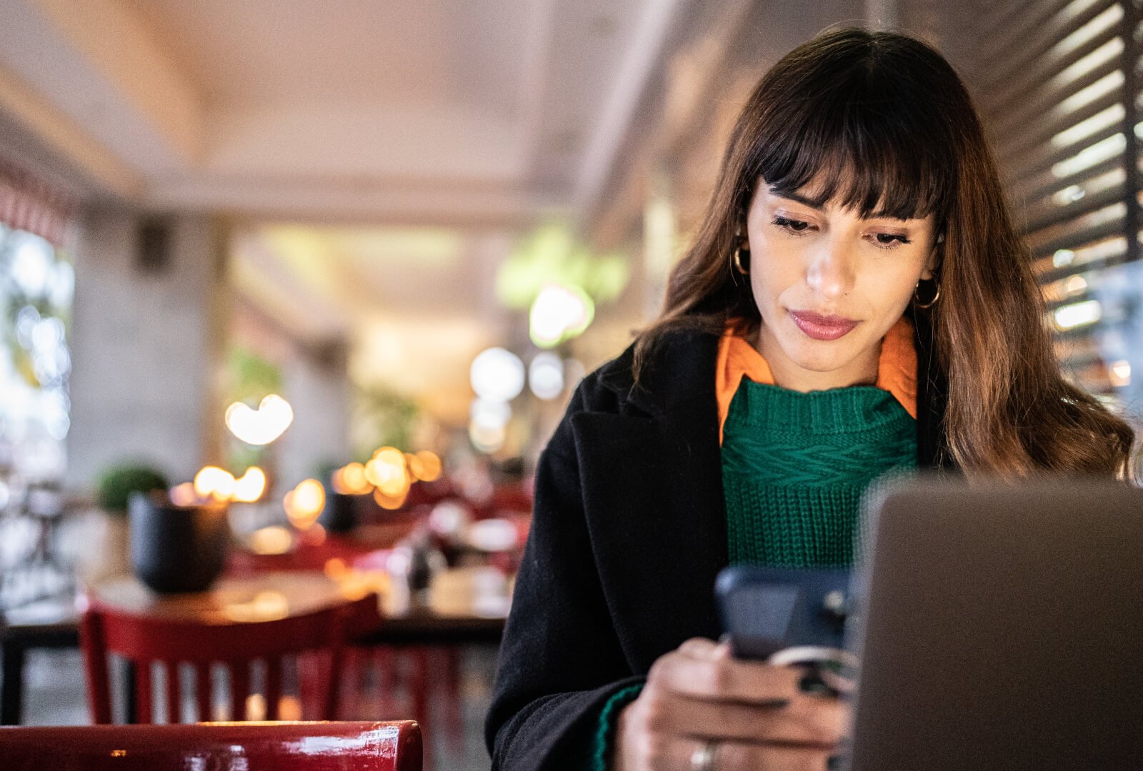 Woman interacting with her smartphone in a brightly lit cafe.