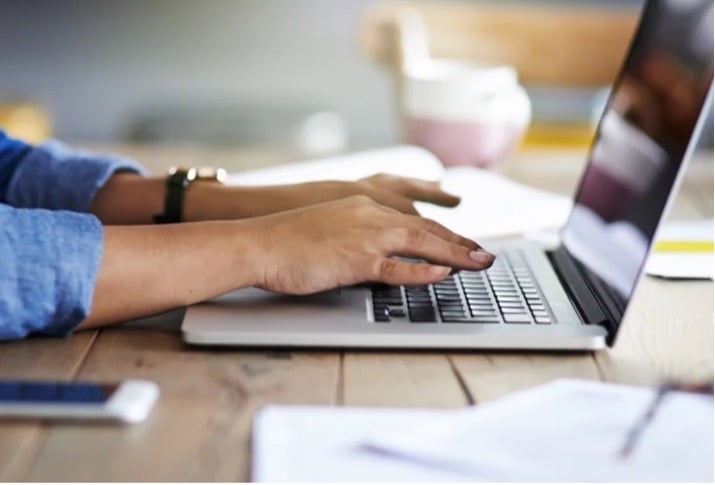 Closeup of a person's hands interacting with a laptop.