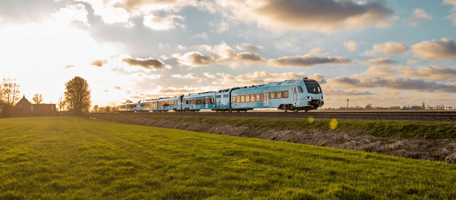 A train moving down the tracks in a brightly lit countryside view.