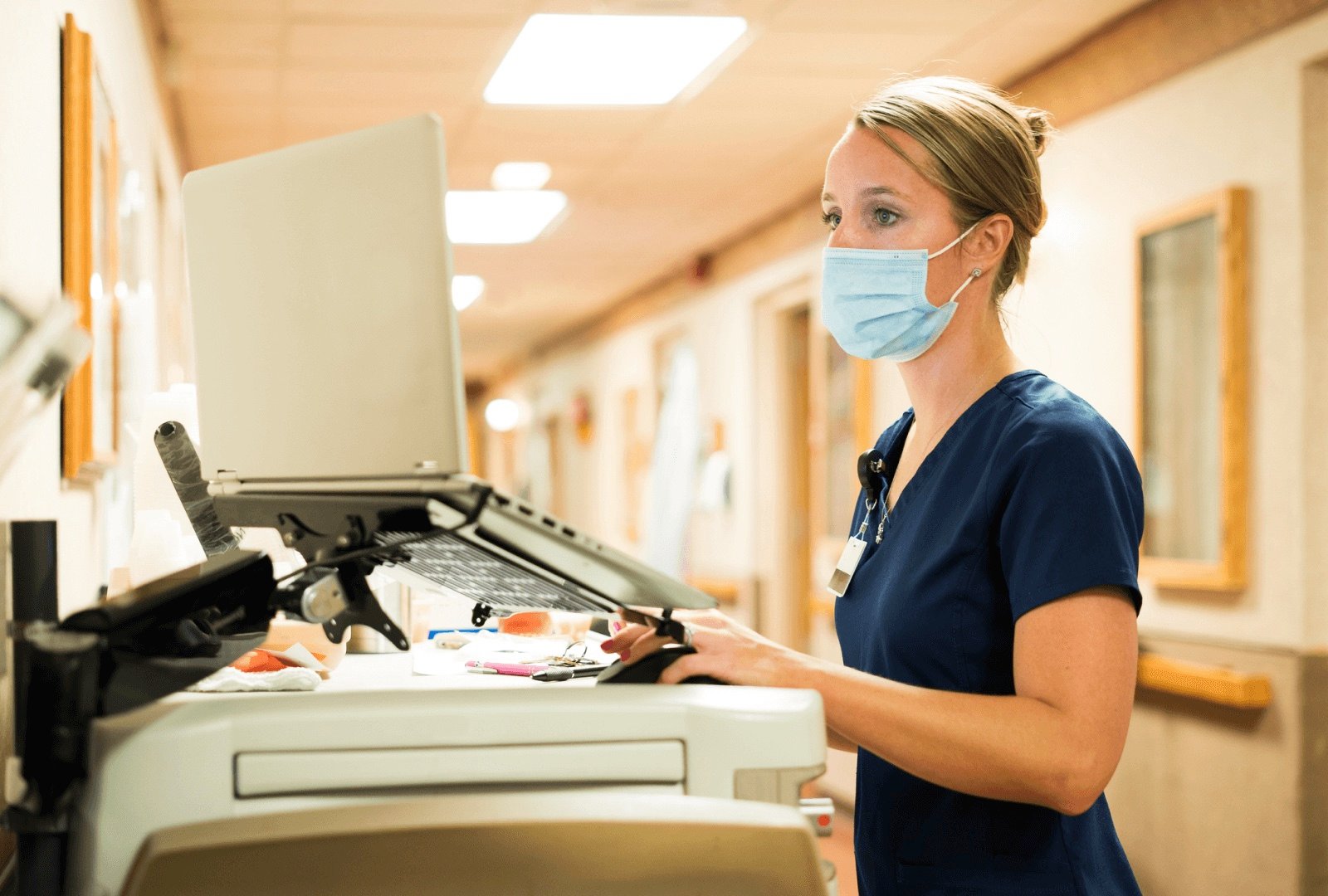 Female nurse with a medical mask working at a mobile workstation.