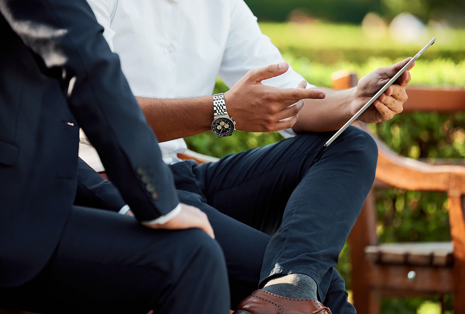 Person on a bench examining a tablet computer.