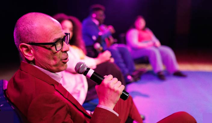 a man speaking into a microphone in a panel discussion