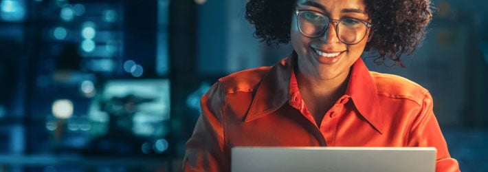 a smiling woman looking at a laptop screen