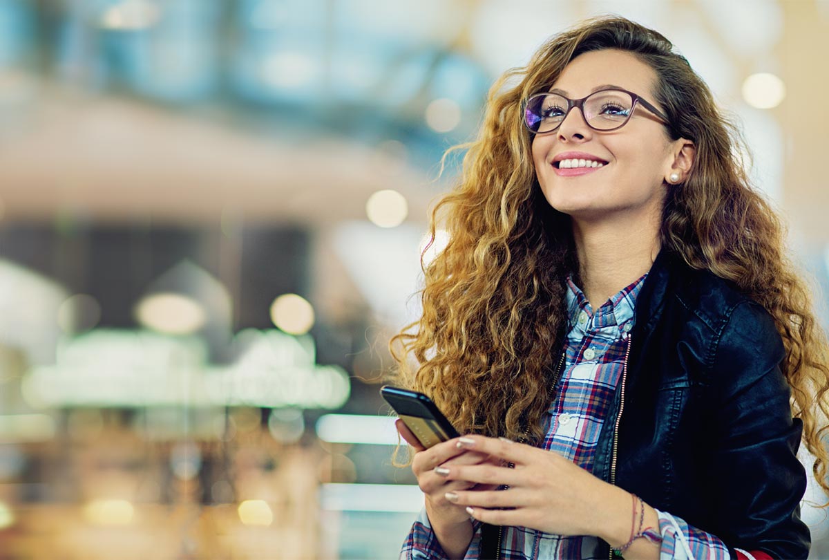 woman holding a phone while looking up into the distance