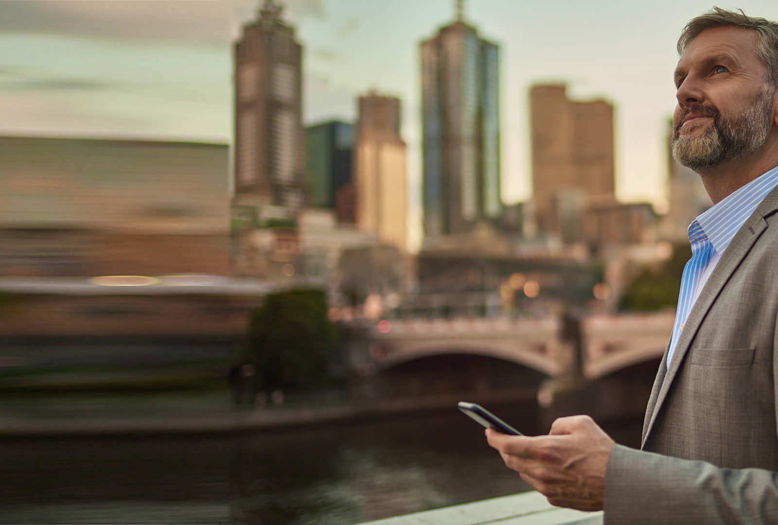 man holding a phone while looking up into the distance