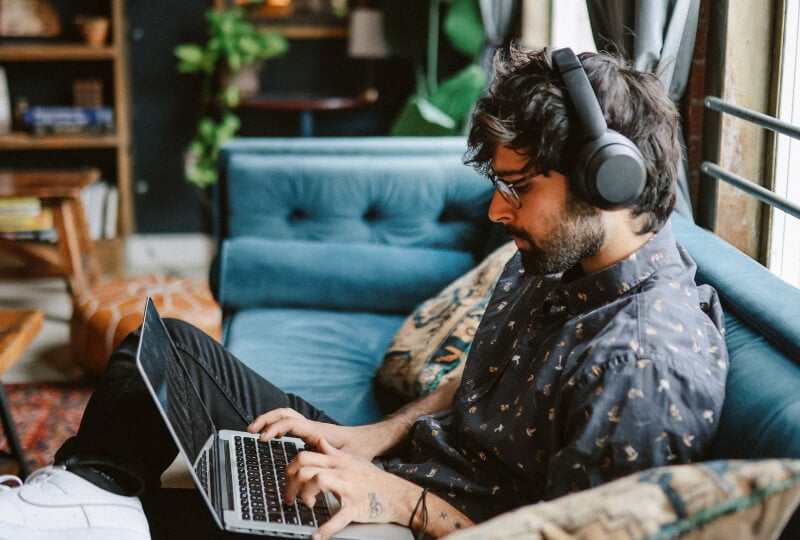 A man with headphones on working on a laptop