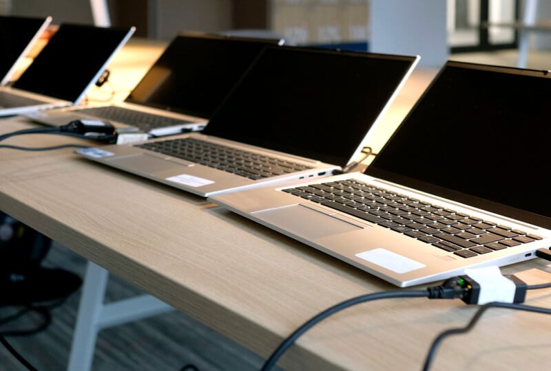 Multiple laptops on top of a desk, with cables running to/from them.