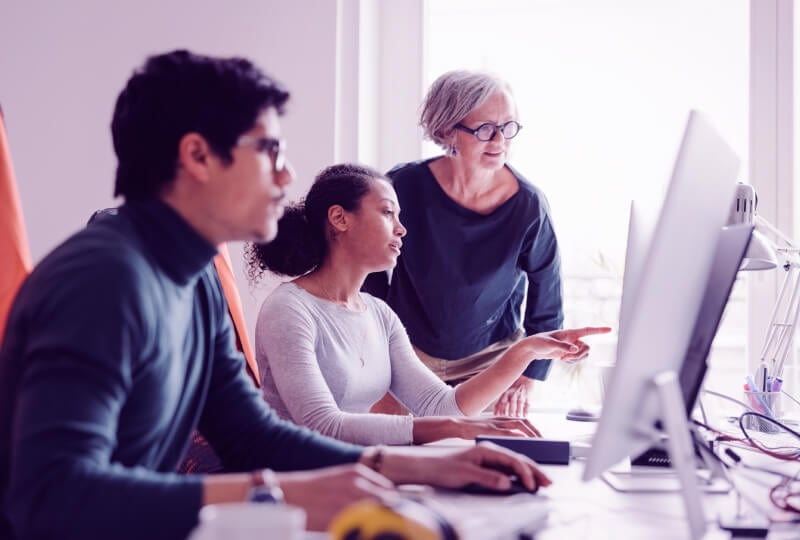 three people looking at a computer