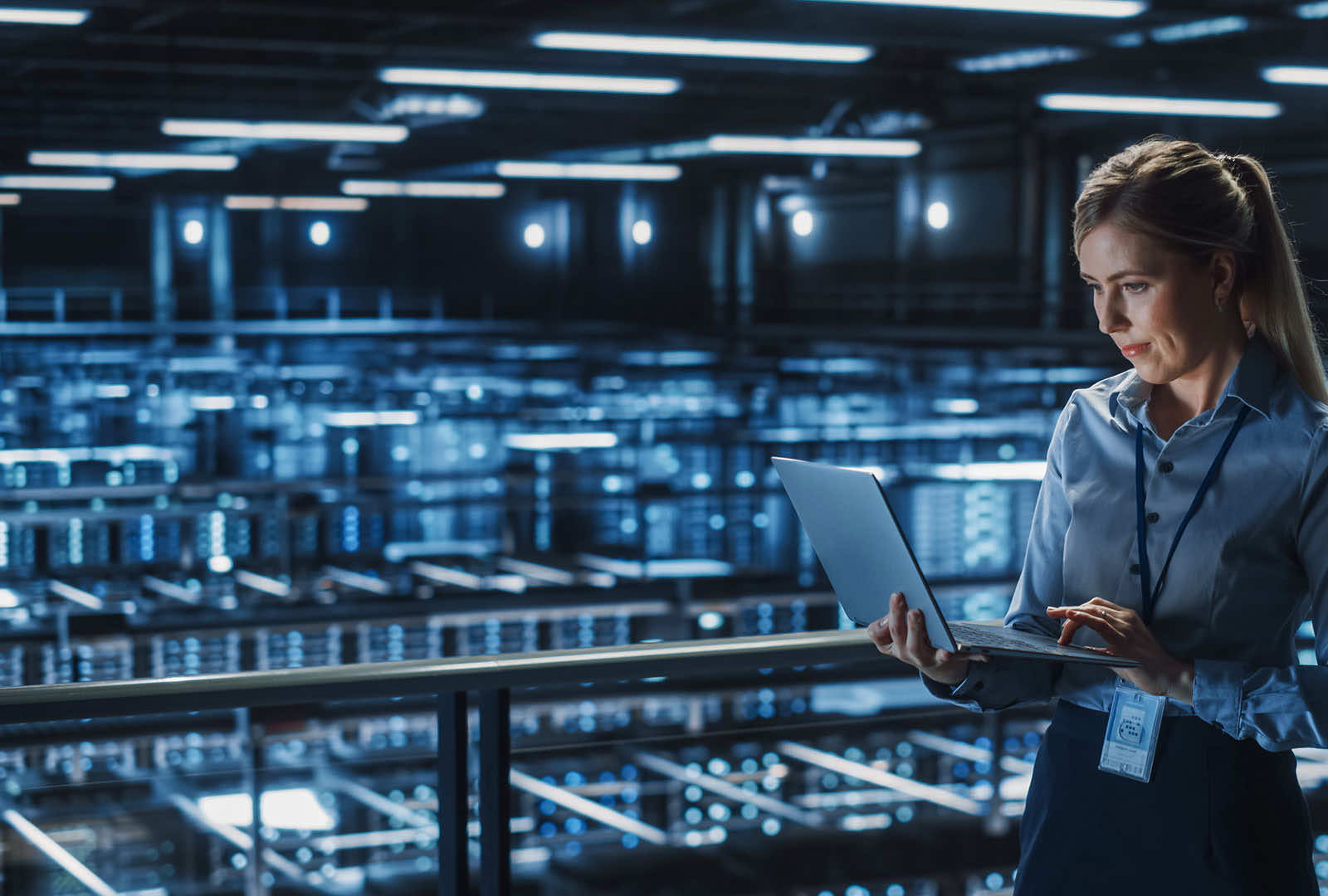 woman in a data center looking at her laptop