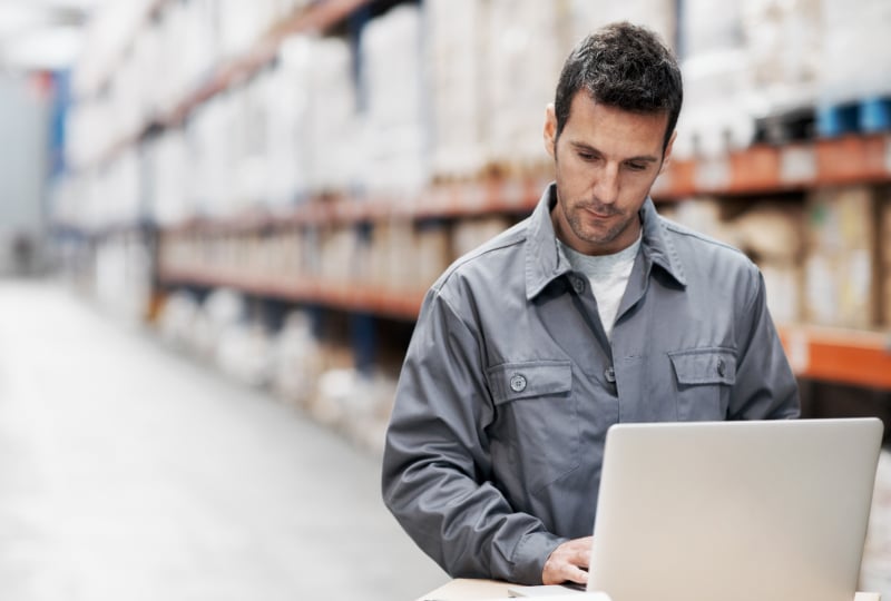 man in warehouse using a laptop computer