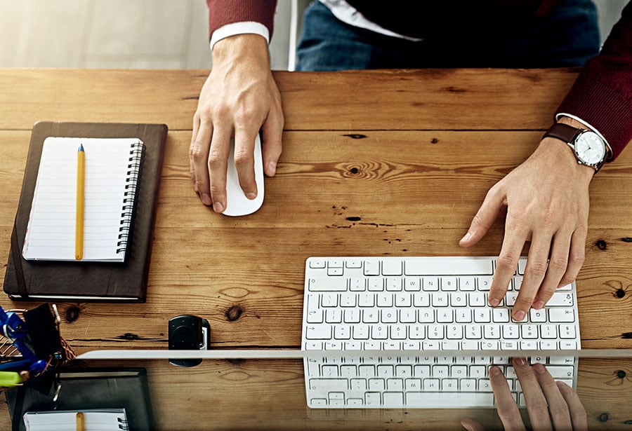 keyboard, notepad, and set of hands from birds-eye-view