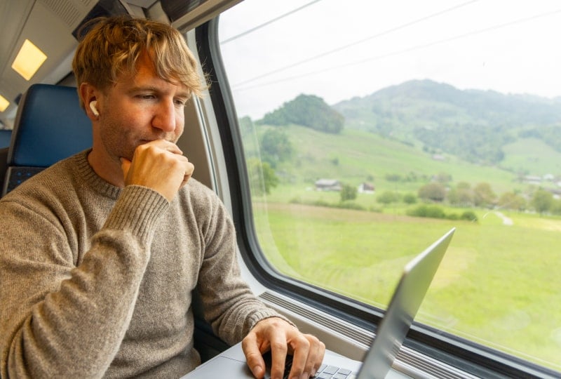 Man in a train car working on a laptop.