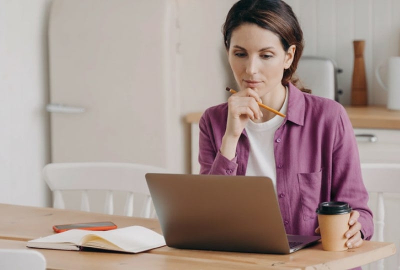 image of a woman sitting in a kitchen working on a laptop computer