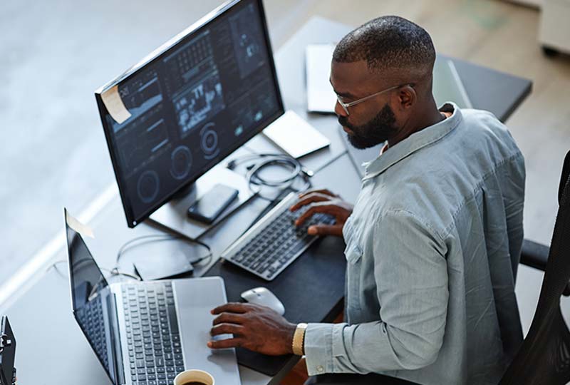 An overhead shot of a man working at a desk while using multiple ChromeOS devices