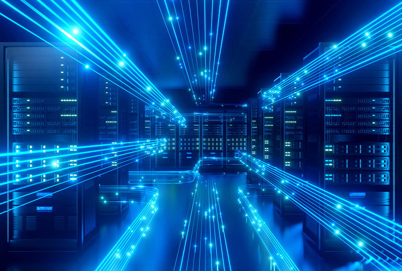 Server room filled with tall racks of computer servers, illuminated by bright blue glowing data lines streaming horizontally and overhead, suggesting high-speed network connectivity in a modern data center.