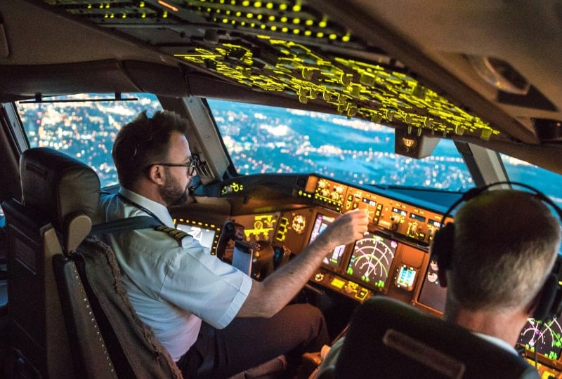 两名飞行员在飞机驾驶舱里白天飞越一座城市