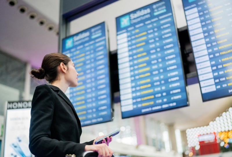 一位女旅客在机场查看航班显示屏
