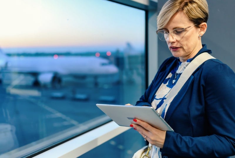 女航班协调员在可俯瞰停机坪的窗边看平板电脑的图片
