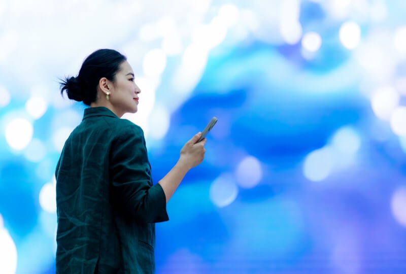 一名女性在色彩丰富的房间内操作智能手机。
