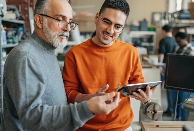 A professor and student interacting with a tablet computer in research room.