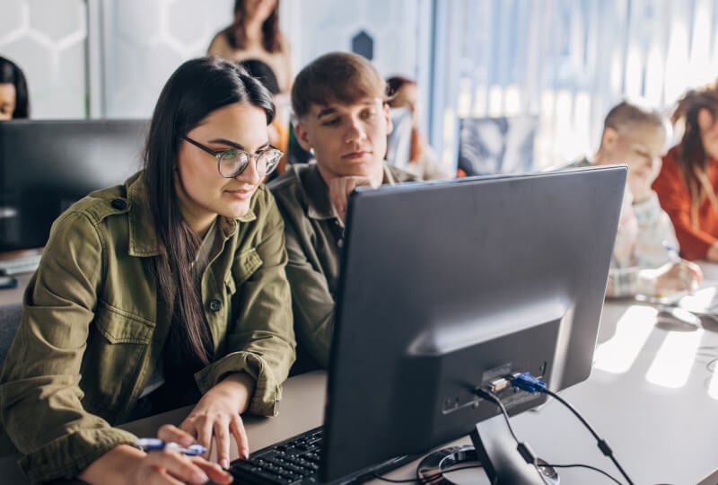 Students working together and interacting with a desktop computer.