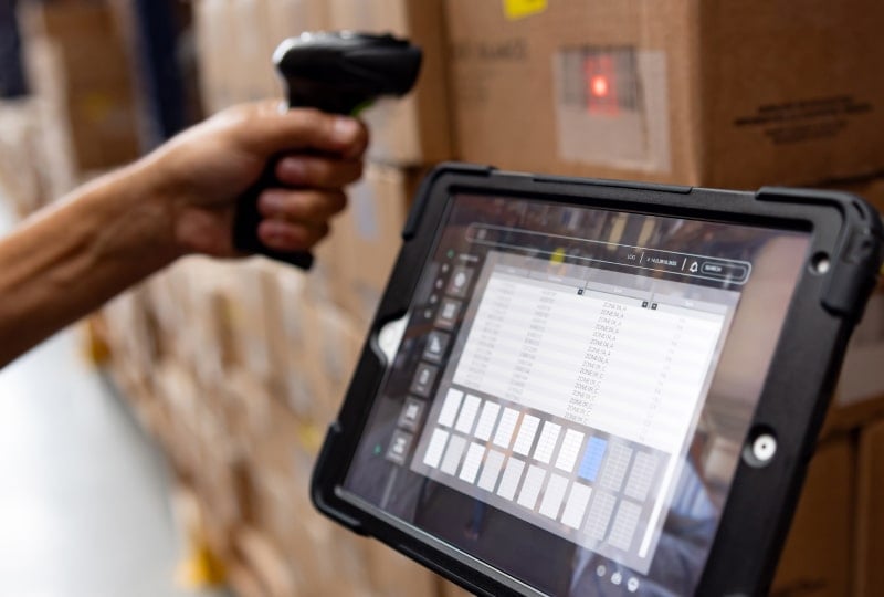 一名工人使用手持扫描仪将箱子上的标签扫描到坚固型移动设备中。