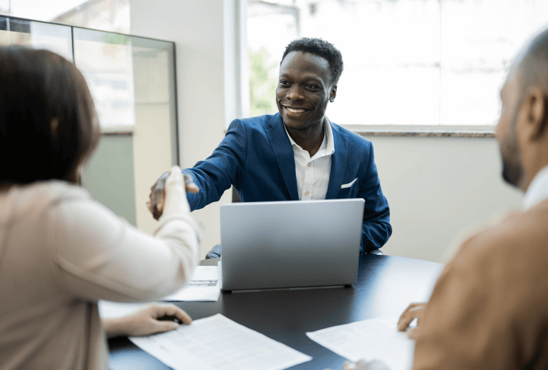 Man shaking hands with a woman in a meeting room.