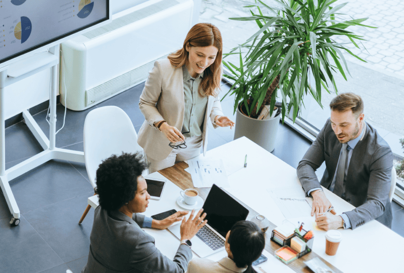 A group of 4 people having a meeting in a brightly lit meeting room.