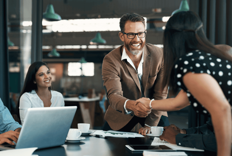 一名男性和一名女性隔着桌子握手。