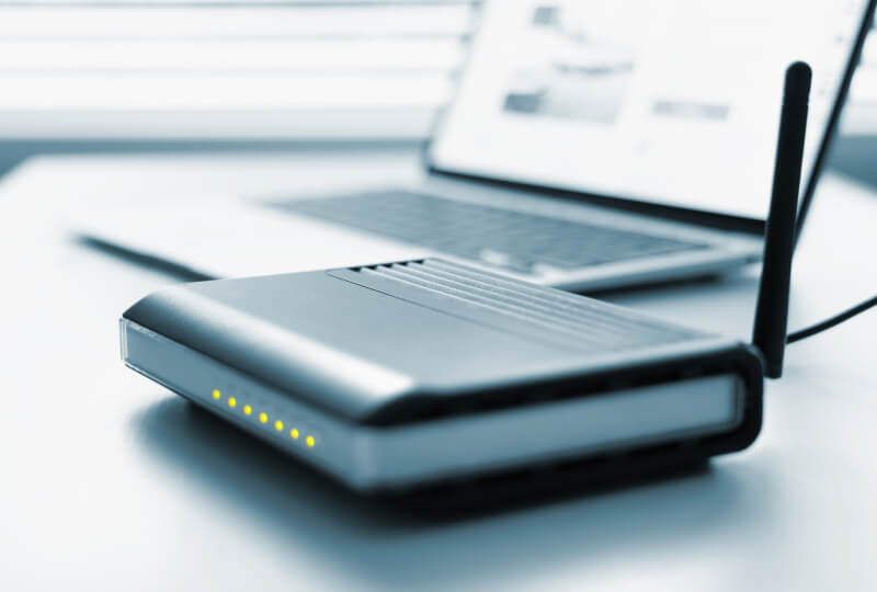 Closeup shot of a router device in front of a laptop.