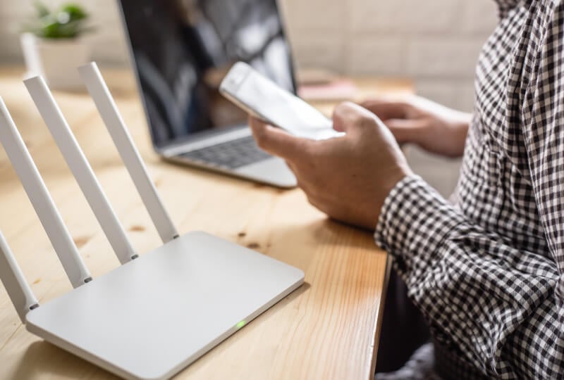 Clouseup shot of a person interacting with a smartphone in front of a router.